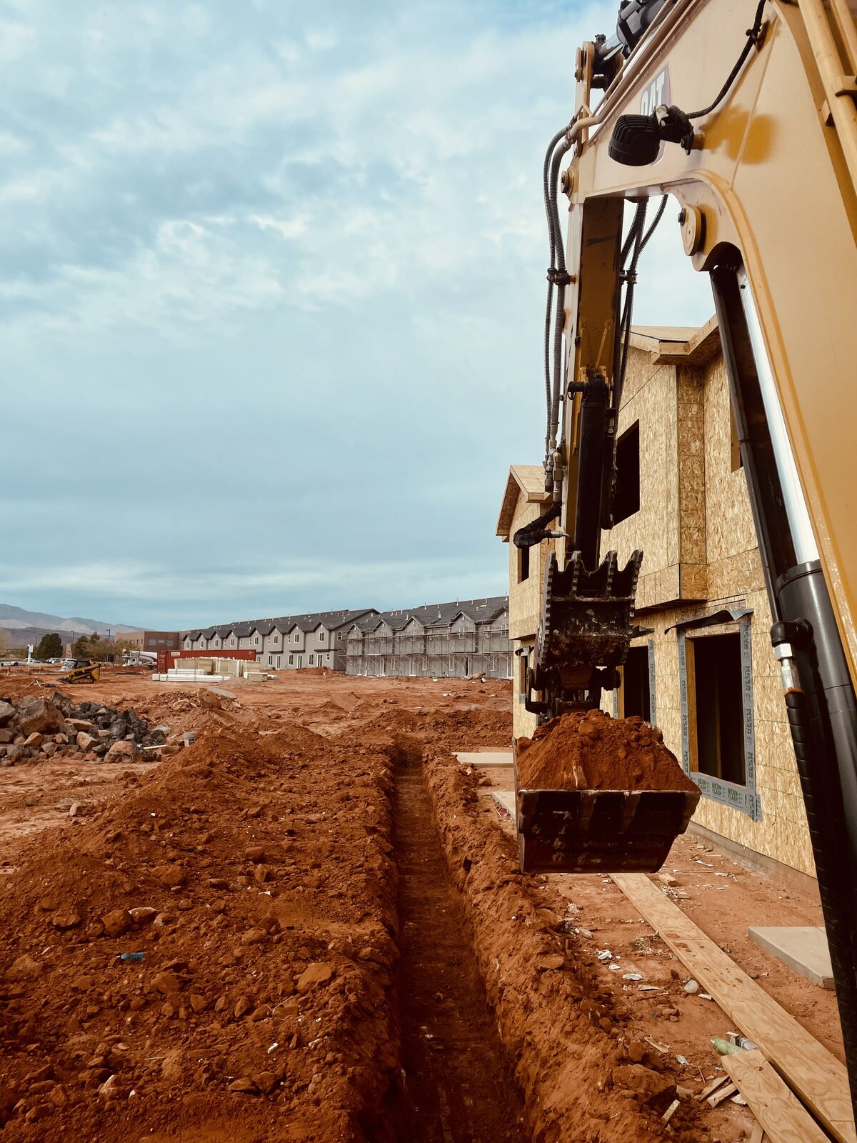 Roxor South excavator trenching a utility line at a townhome construction site in Washington City, Utah
